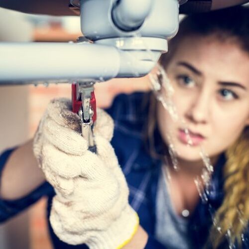 A Plumber Repairs a Leaking Pipe.