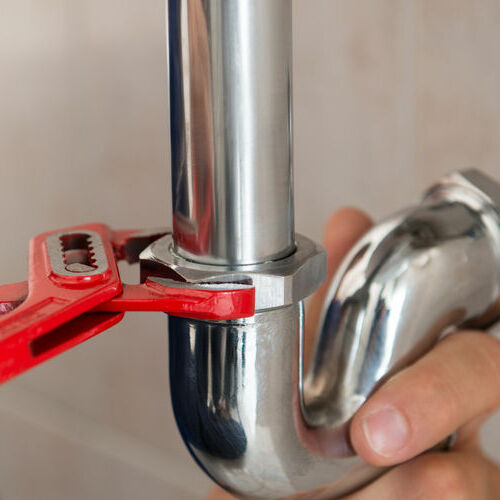 A Plumber Uses a Wrench to Repair a Pipe.