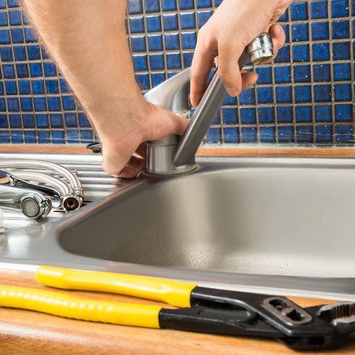 A Plumber Installs a Faucet