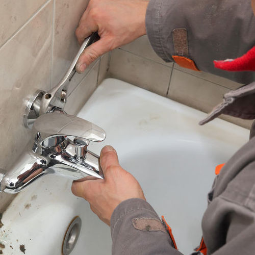 A Plumber Repairs a Bathtub Faucet