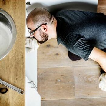 A Plumber Examines Problems Under a Sink